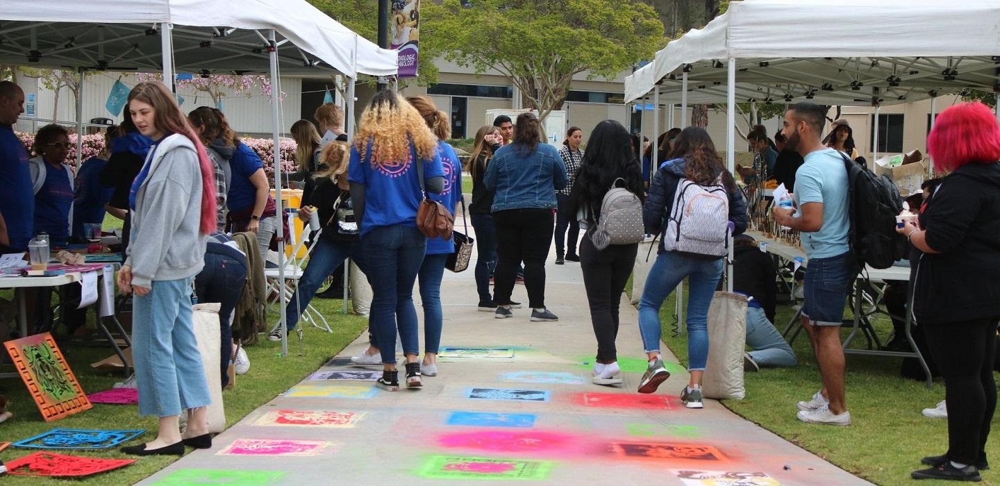 Students stop by booths at an outdoor fair on campus.