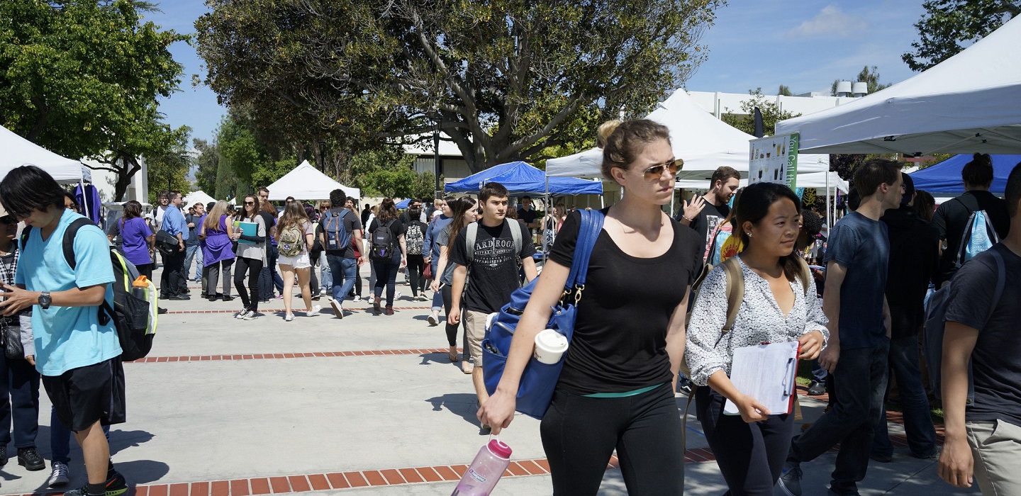 Students walk beside booths along Raider Walk.