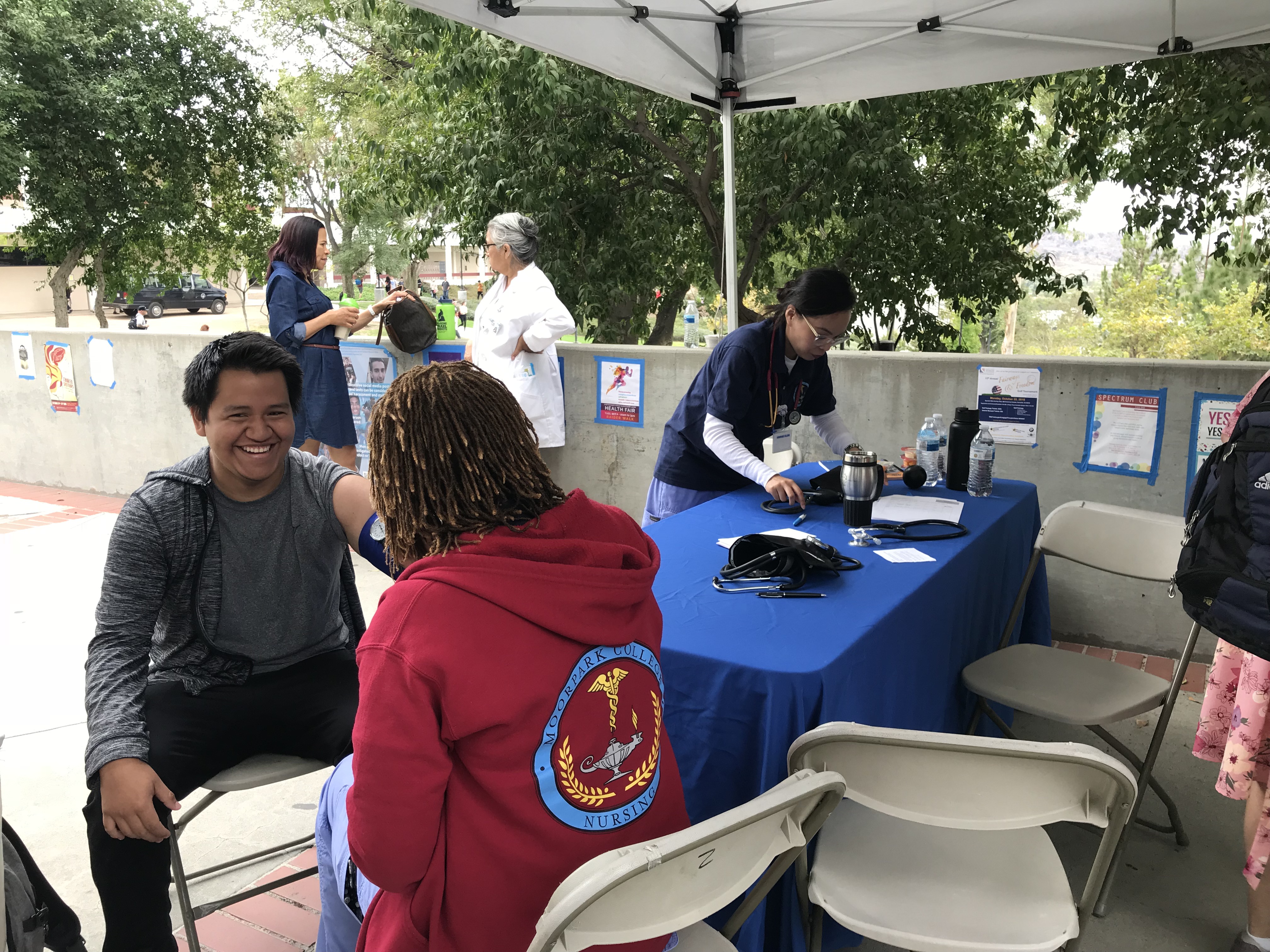 Smiling Moorpark College student gets his blood pressure measured by student nurse at the MC Health Fair