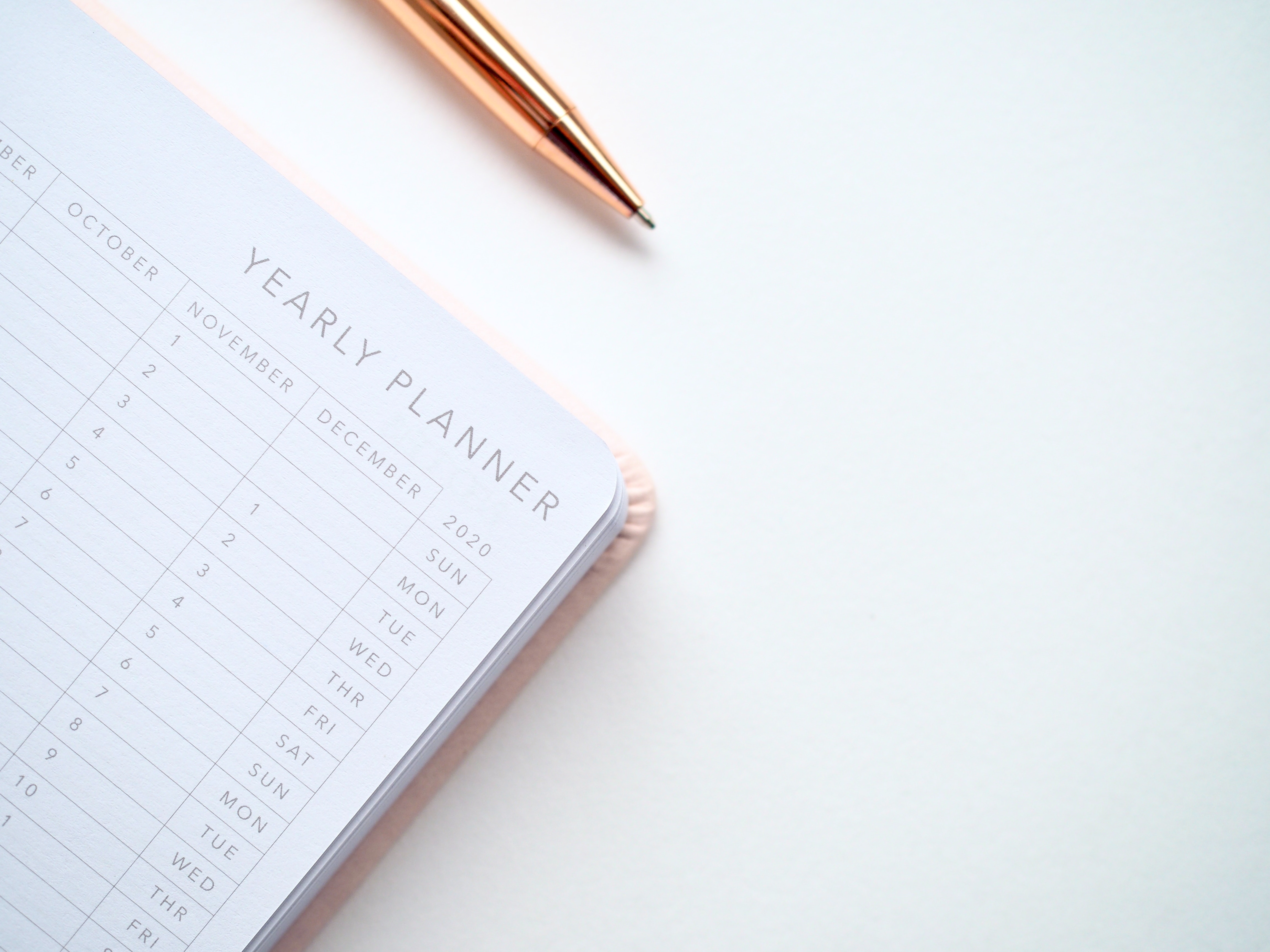 Yearly planner on a table with a rose gold pen