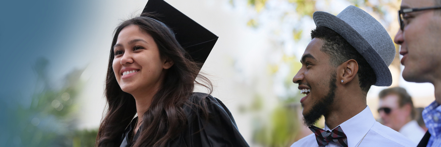 Male with cool hat looks on at woman grad