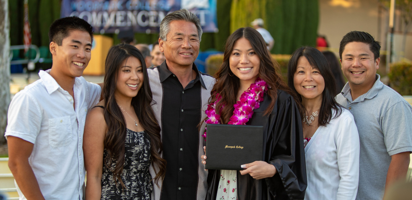 A family poses around their graduate at commencement.
