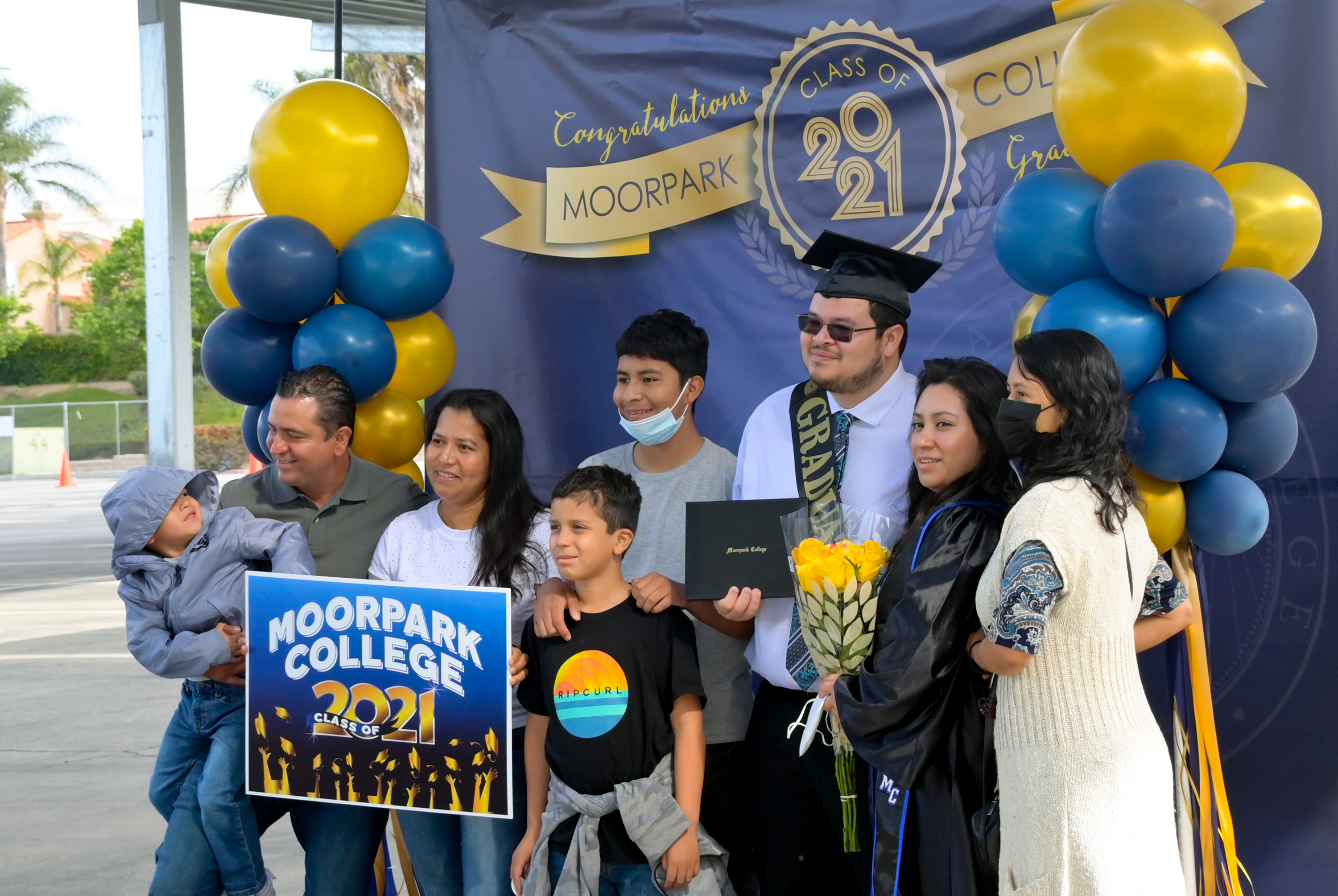 A family poses proudly for a photo with their MC graduate