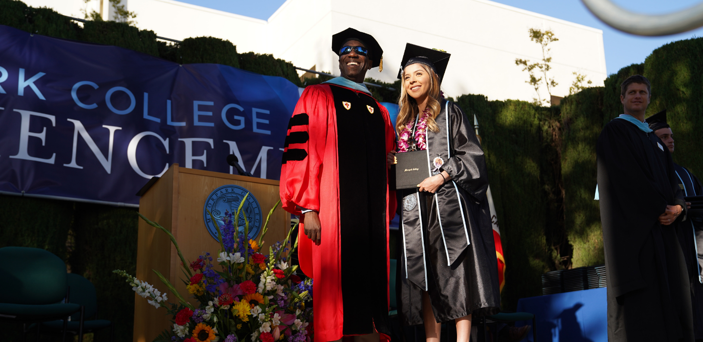 Moorpark College president Dr. Julius Sokenu poses for a photo with a student as she receives her diploma cover at Commencement.