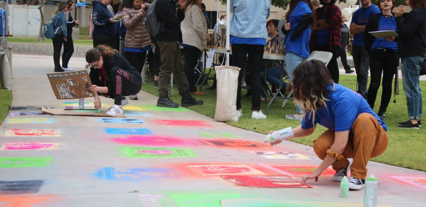 Students create chalk art on the cement walkway during the MakerSpace event