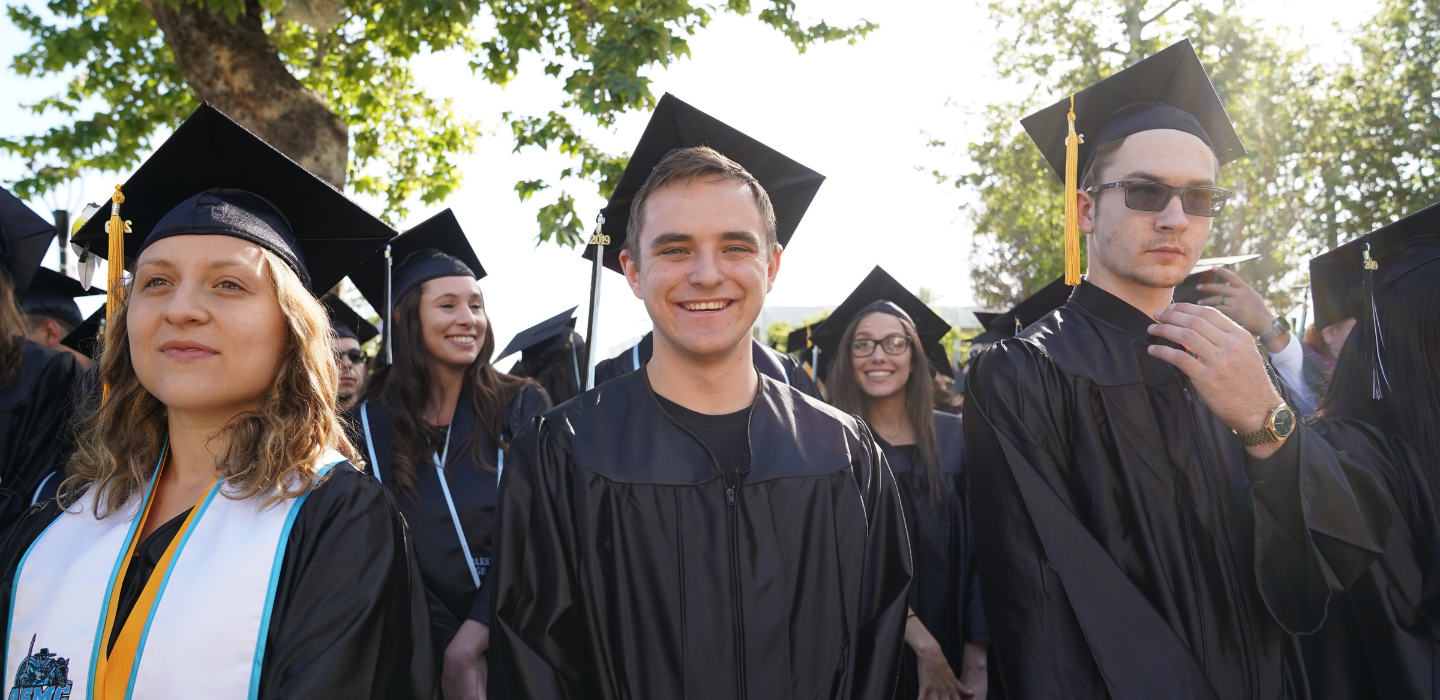 Three students are show smiling during commencement