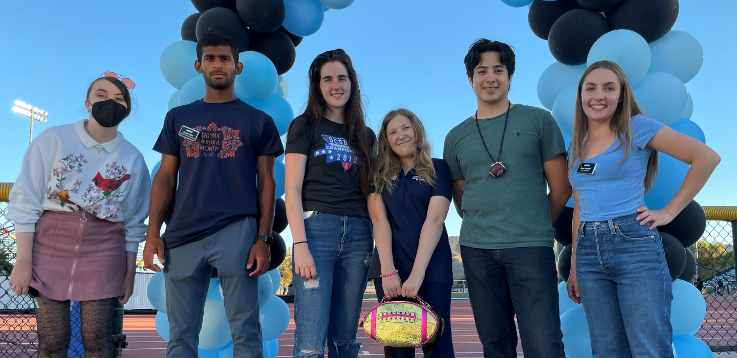 Associated Students pose for photo at home football game.