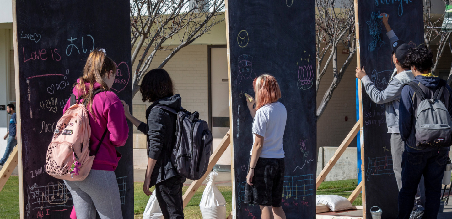 Students write on large chalkboards as part of a campus event