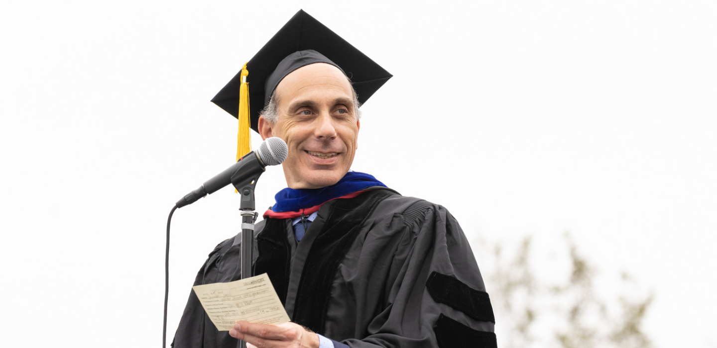 2023 Academic Senate President Dr. Erik Reese reads a name card.