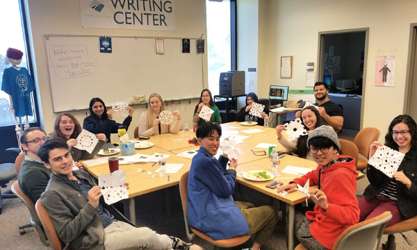 Writing tutors posing with their paper snowflakes at the Writing Center