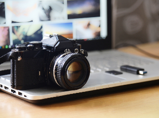 a digital camera and a flash drive sitting on top of a laptop.