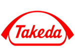 Takeda Pharmaceutical Co. logo in Red.  The name Takeda is covered in a red arch that connects with a red border below the name Takeda 