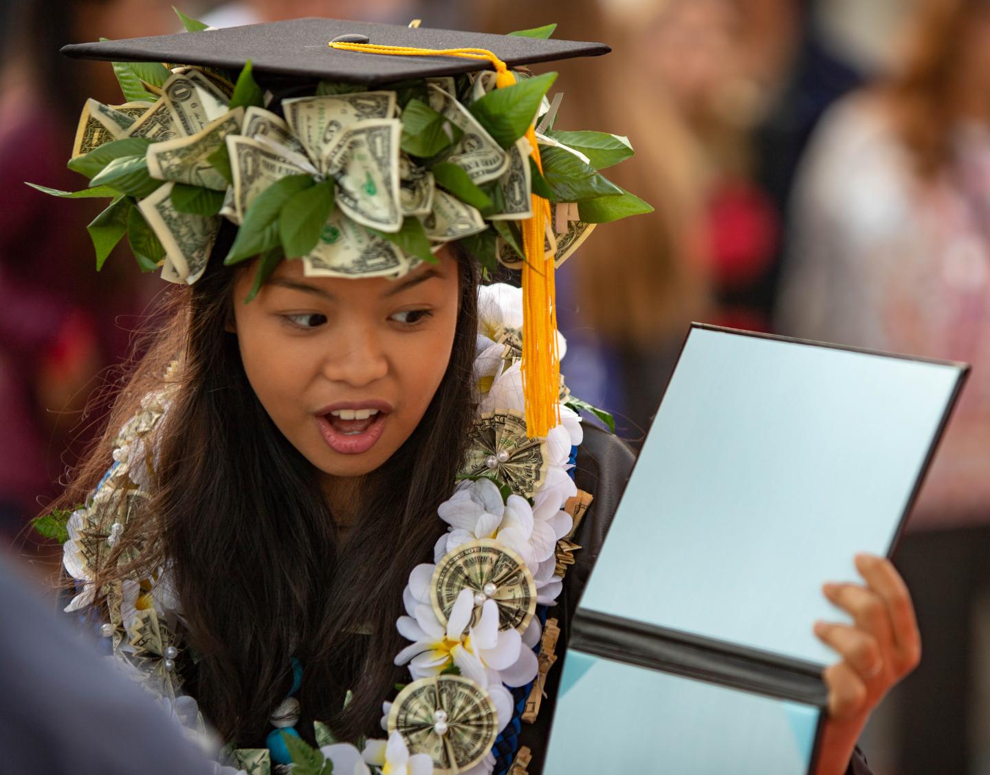 A graduate looks surprised to find her diploma cover empty at graduation.
