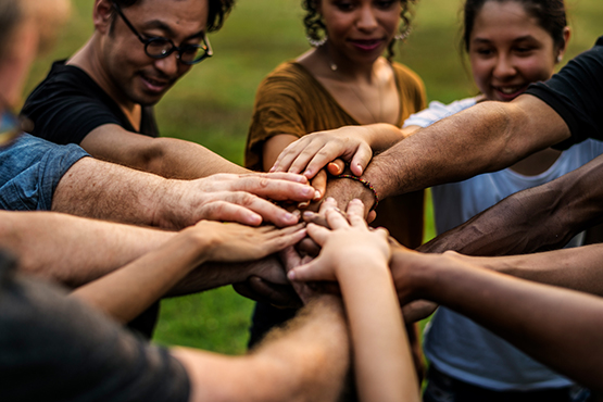 diverse group gather hands together in center of photo