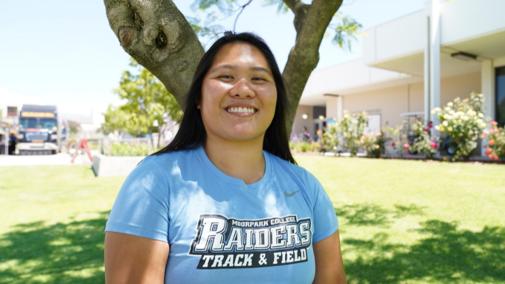 Patricia smiles for the camera in front of a grassy background