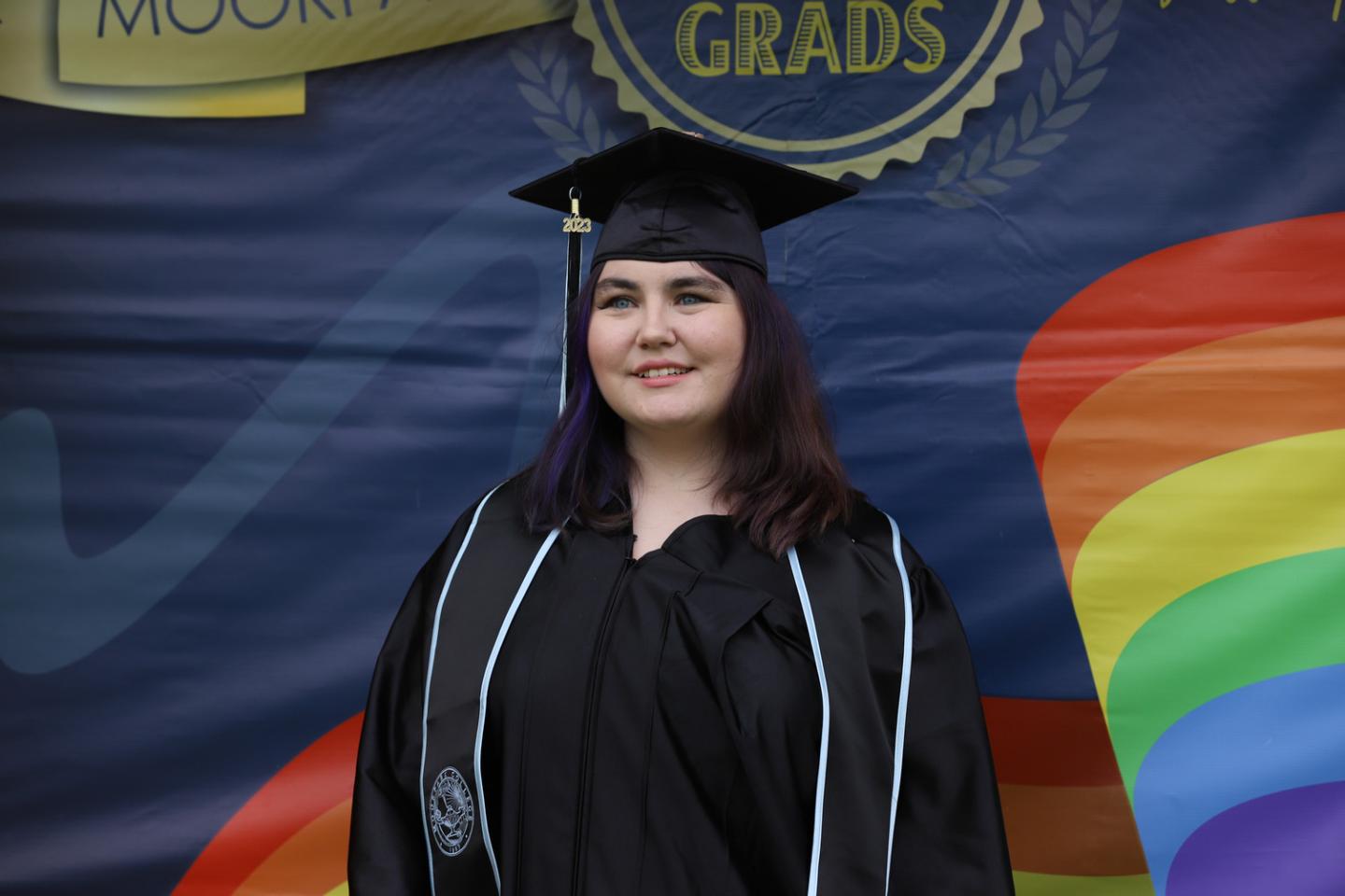 A graduate in regalia is shown smiling for a picture