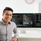 Male student is sitting at a computer with two large monitor