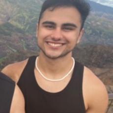 Photo of Ryan smiling with a scenic mountain scape behind him 