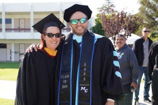 Two faculty members smile together for the camera on commencement day.