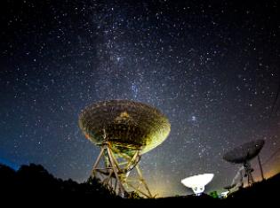 A night sky with satellites pointing upward in the foreground.