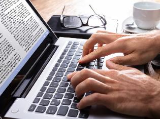 Hands typing on a laptop keyboard.