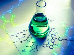 A beaker sitting on top of notes of a molecular diagram.