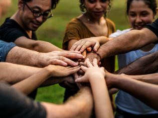 A group of diverse people with hands gathered in center