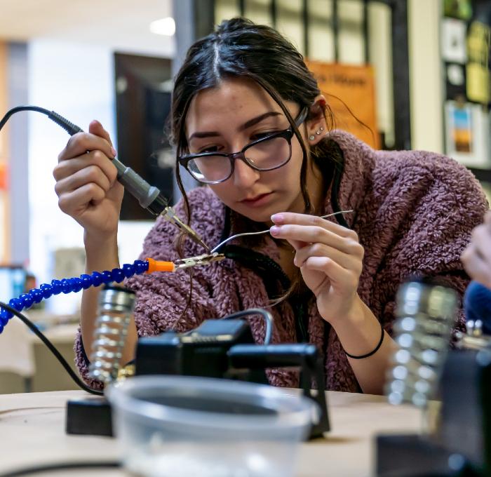 female student using a soldering gun