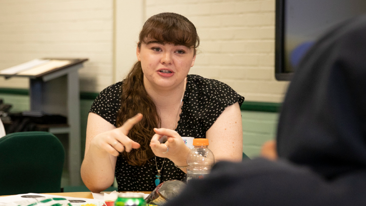 A female student discusses a topic with another student during an MC LEADS session.