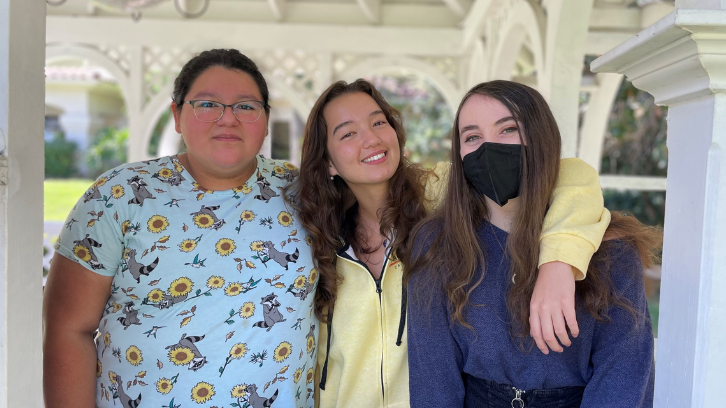 Three students smile for a photo together.