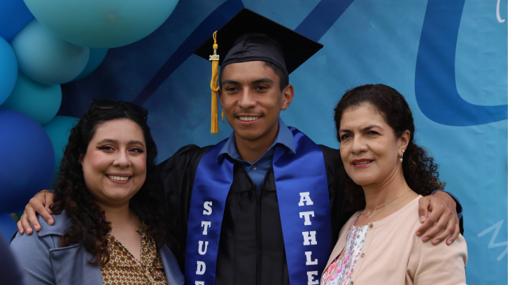 A student poses proudly with family.