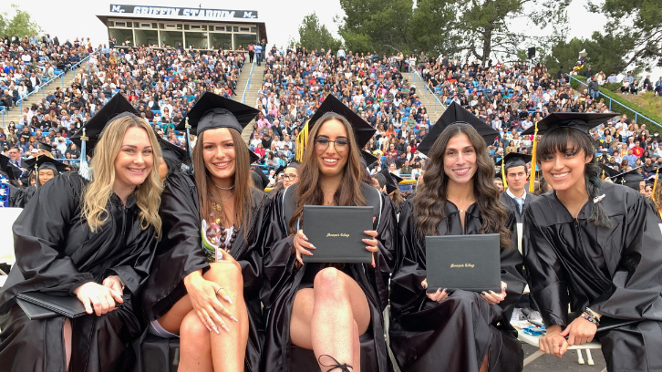 Female graduates pose for picture after receiving diploma covers.