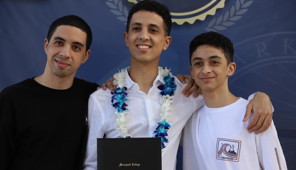 Moorpark College graduate holding his degree, posing with family members.