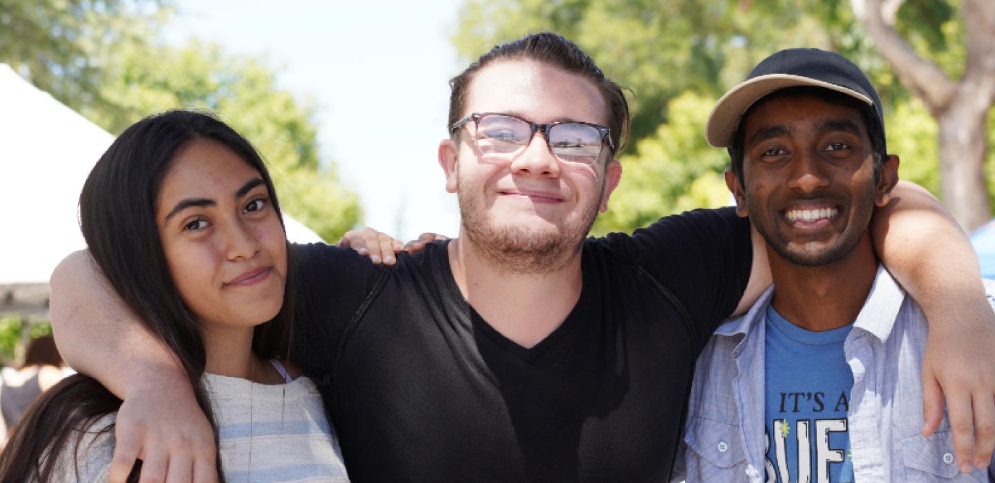 three students with arms around each other