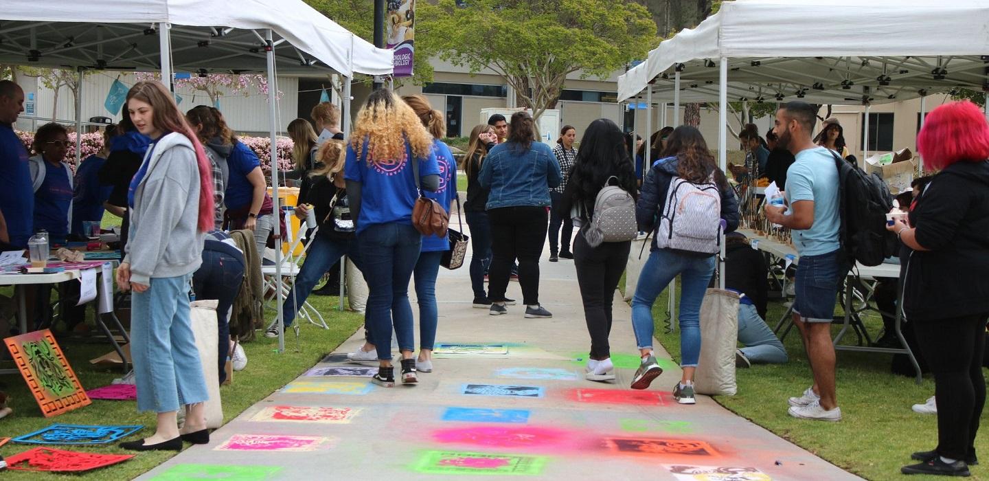 Students stop by booths at an outdoor fair on campus.