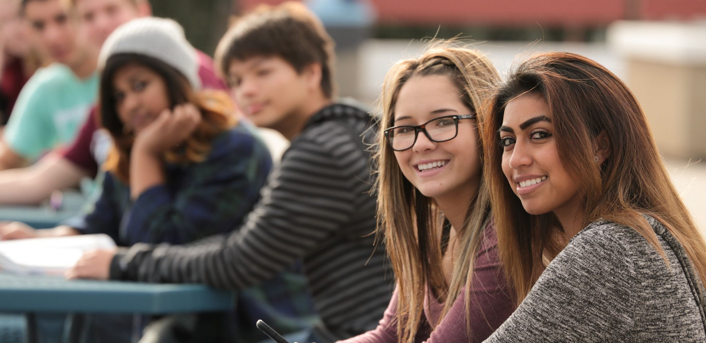Students sit at round outdoor tables on the Moorpark College campus.
