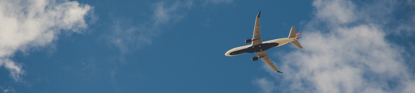 Airplane shown in the distance in the blue sky with clouds