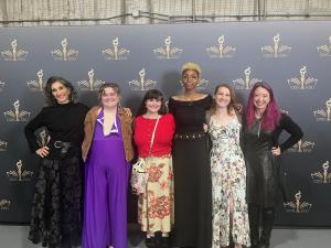 Professor Risdana standing proudly with Theatre Arts students at a formal event