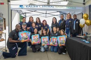 President Julius Sokenu, Raider Central Basic Needs staff, and VCCU representatives pose with donation bags of basic needs supplies for students. 