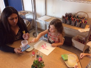 female child painting with female student worker